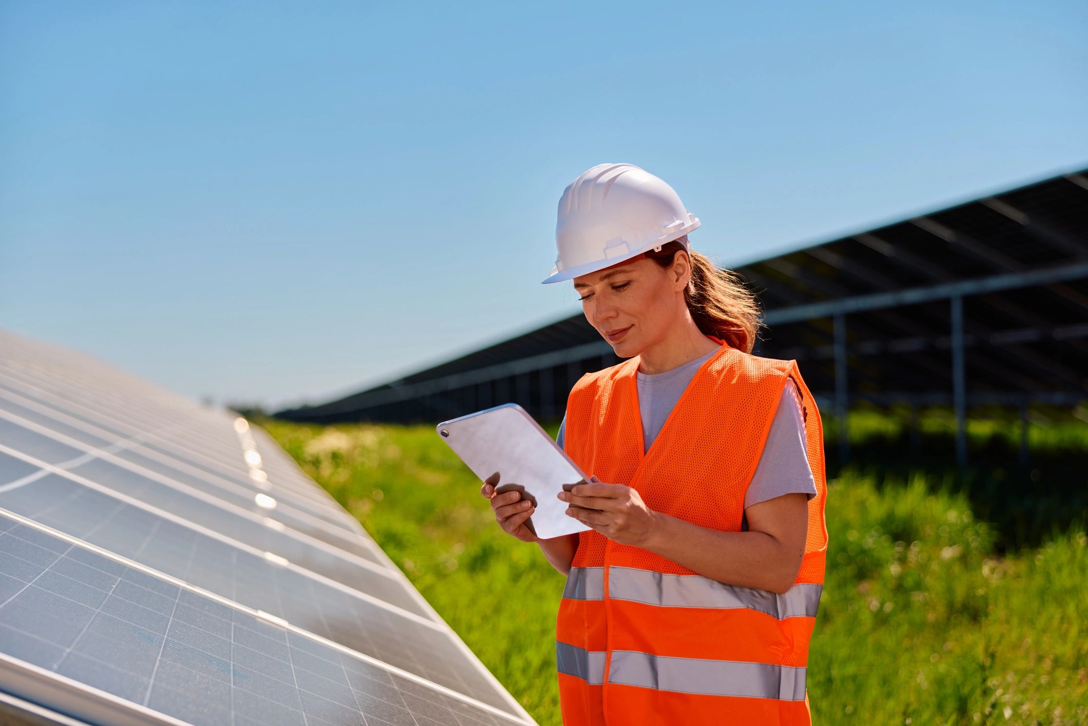 Female engineer inspecting solar panels for renewable energy